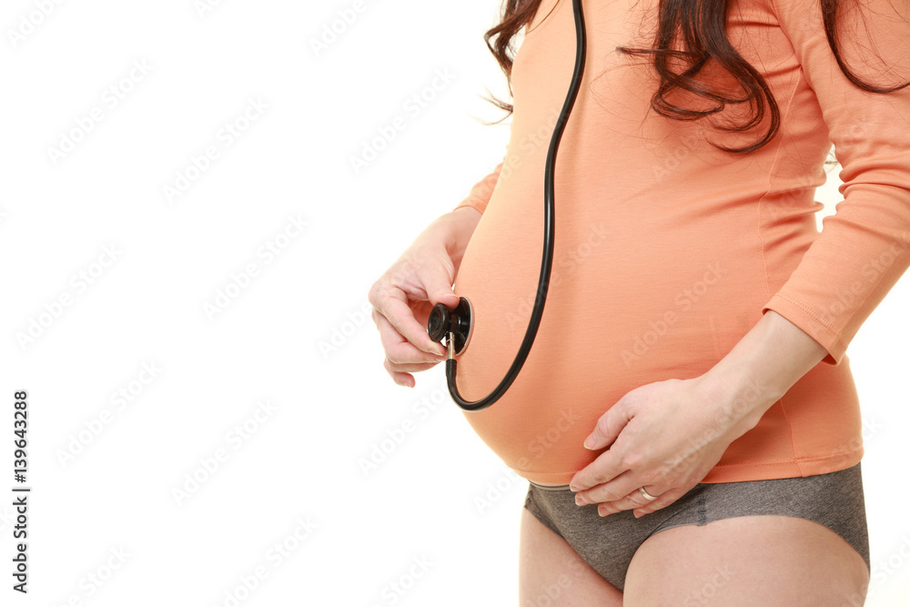 聴診器を自分のお腹にあてる臨月の妊婦 Stock Photo | Adobe Stock
