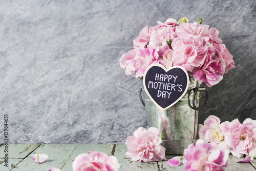 Pink carnation flowers in zinc bucket with happy mothers day letter on wood heart