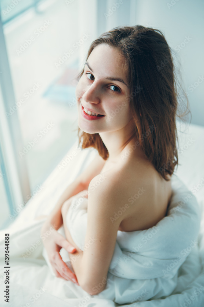 Close up portrait of smiling young beautiful Caucasian woman sitting in bed after waking up, indoors at home early morning, lifestyle, toned with filters Close up portrait of smiling young beautiful Caucasian woman sitting in bed after waking up, indoors at home early morning, lifestyle, toned with filters