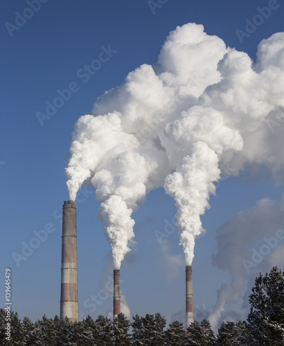 Smoking chimney of industrial buildings complex.