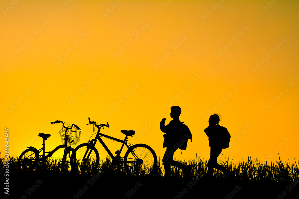 Silhouette of children with bicycle on grass field at the sky sunset, color of vintage tone and soft focus concept journey in holiday Silhouette of children with bicycle on grass field at the sky sunset, color of vintage tone and soft focus concept journey in holiday