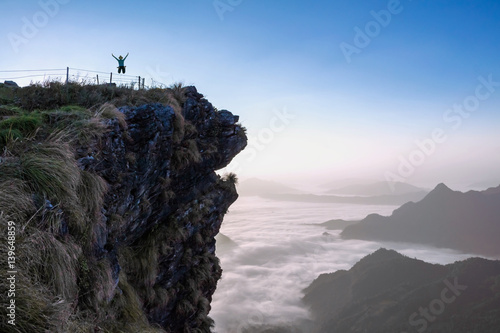 Woman jumps on a cliff below filled with mist., Attractions Phu Chi Fah, Chiang Rai, Thailand.