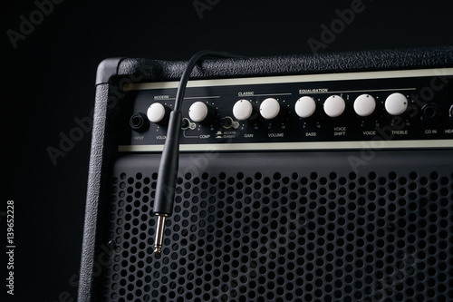 Close up of Black guitar amplifier with jack cable on black background.