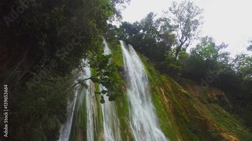 Bottom view of the magnificent waterfall falling in green forest photo