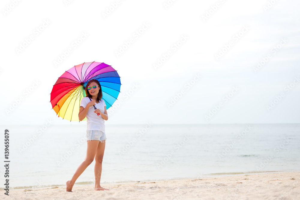 Young women jumping with umbrella and happy on the beach. Travel and Vacation. Freedom Concept