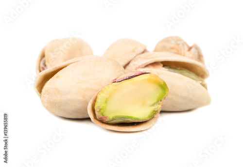 Salted pistachio nuts with a half on a white background