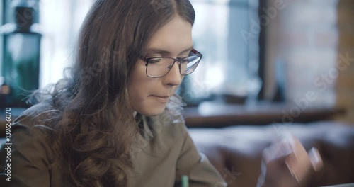young girl working at a laptop and drinking coffee in a cafe, distant work, freelancer