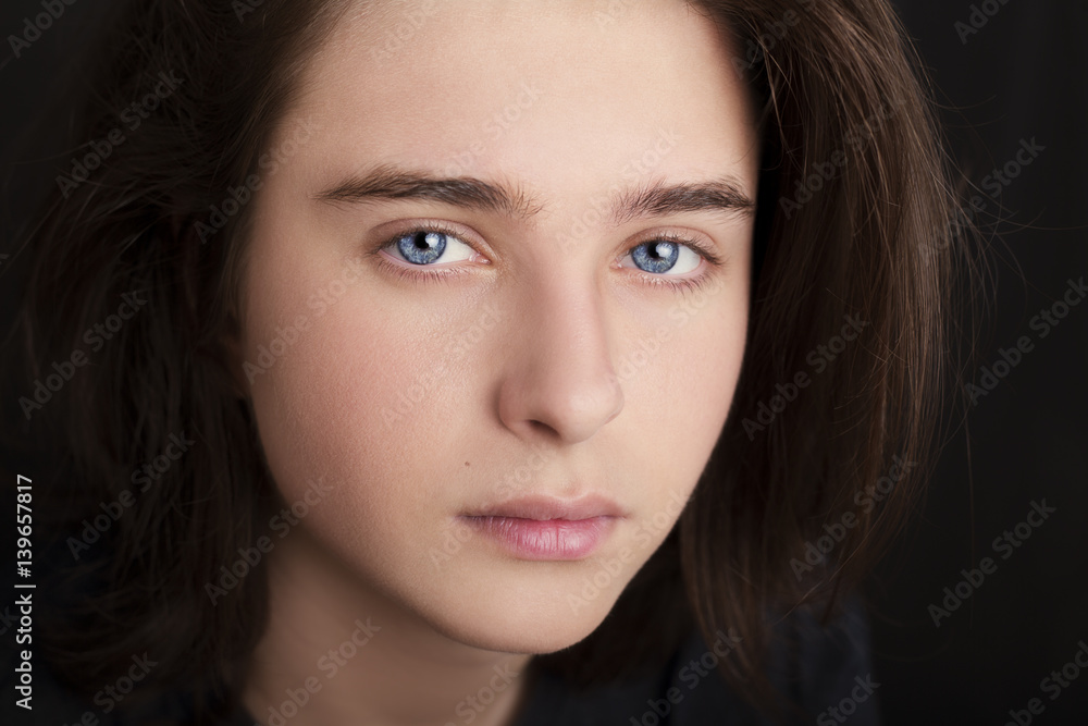 A portrait of a handsome blue eyes teenager on dark background A portrait of a handsome blue eyes teenager on dark background