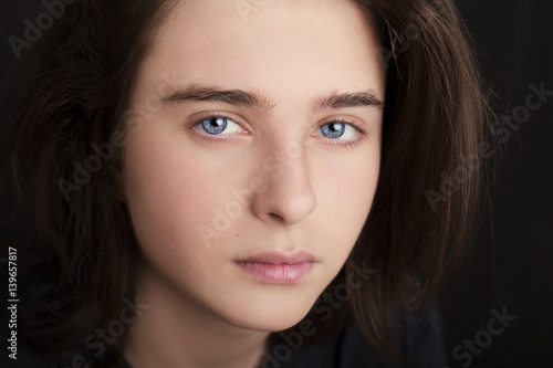 A portrait of a handsome blue eyes teenager on dark background