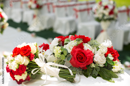 Wedding ceremony outdoors. Bouquet with red flowers.