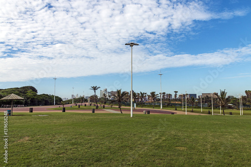 Green lawn paved promenade against city skyline in Durban