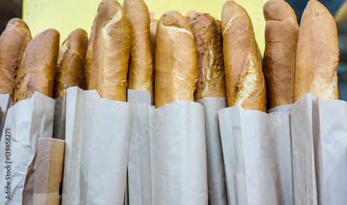 Fresh baked rustic bread loaves in paper bags on wooden shop shelf photo