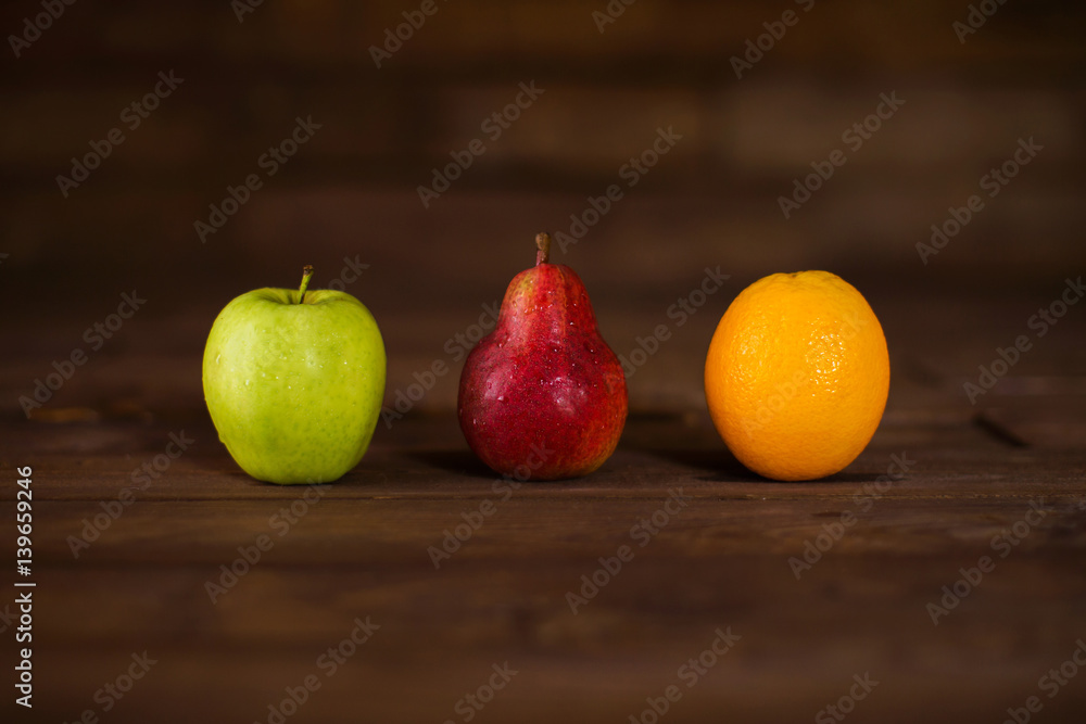 Apple, pear and orange on a wooden table