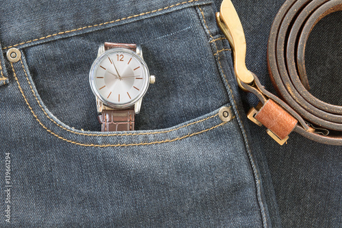 Wrist watch and leather belt on jeans