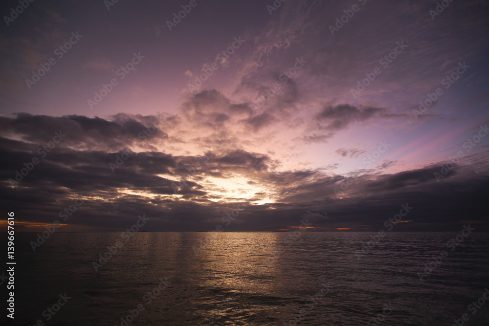 Sunset sky which reflected in sea water with calm waves. Beautiful scenery of a Indian Ocean with sunrise