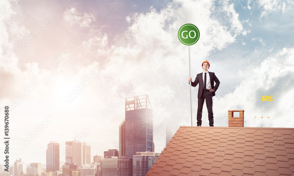 Businessman in suit on house top with ecology concept signboard. Businessman in suit on house top with ecology concept signboard.