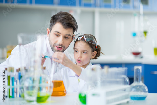 Man teacher and girl student scientists making experiment  in chemical lab