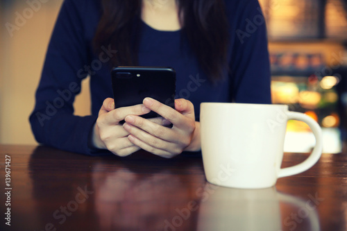 Asian female with hands typing text message and coffee