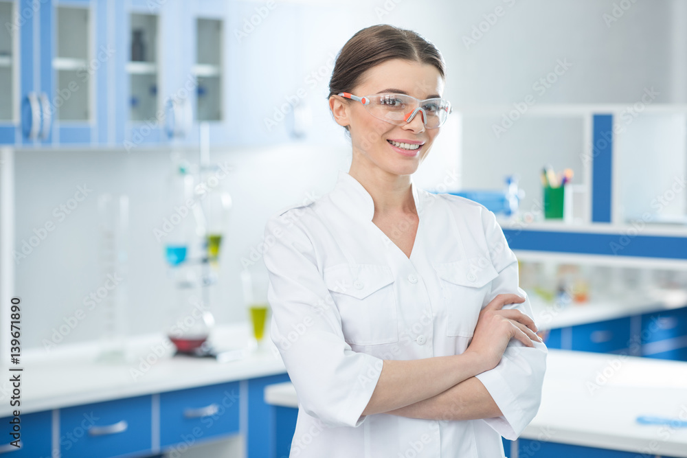 portrait of smiling scientist in white coat and protective glasses in lab portrait of smiling scientist in white coat and protective glasses in lab