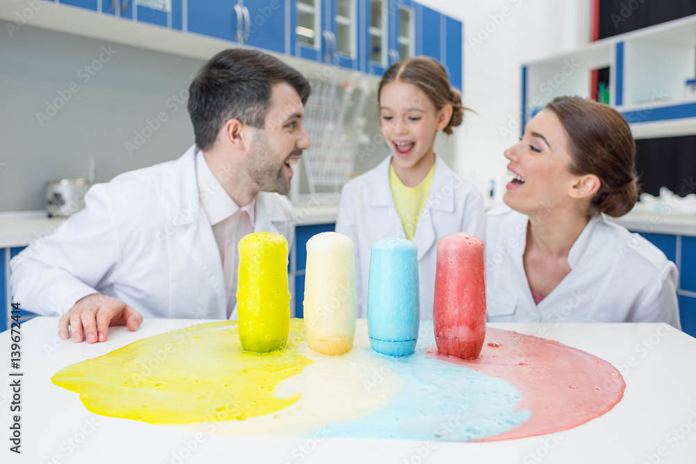 portrait of cheerful teachers and girl student scientists making experiment in lab