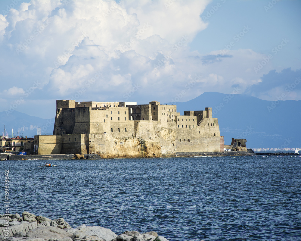 Castell del Ovo (Egg Castle) in Naples, surronded by the sea, and mount vesubio can be seen in the background
