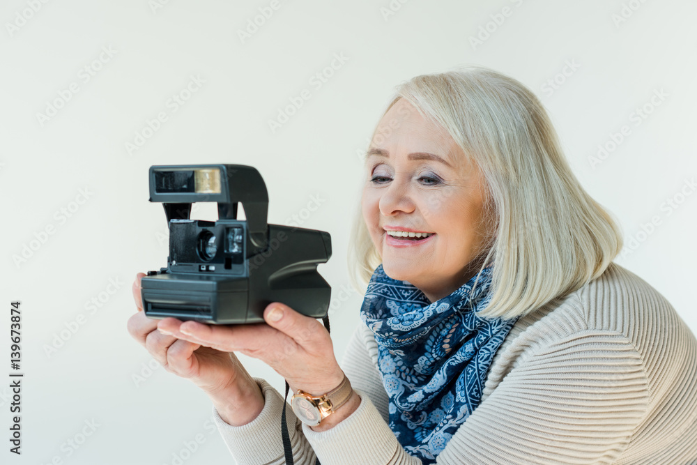 portrait of smiling senior woman holding retro photo camera on white portrait of smiling senior woman holding retro photo camera on white