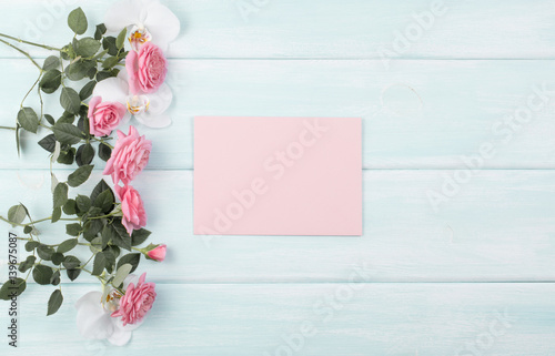 Wooden background with roses and orchid and empty notebook with place for text