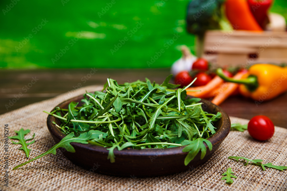 Arugula leaves in bowl. Fresh salad. Carrot, pepper and cherry tomatoes. Natural raw vegetables. Organic bio food on rustic wooden table. Arugula leaves in bowl. Fresh salad. Carrot, pepper and cherry tomatoes. Natural raw vegetables. Organic bio food on rustic wooden table.