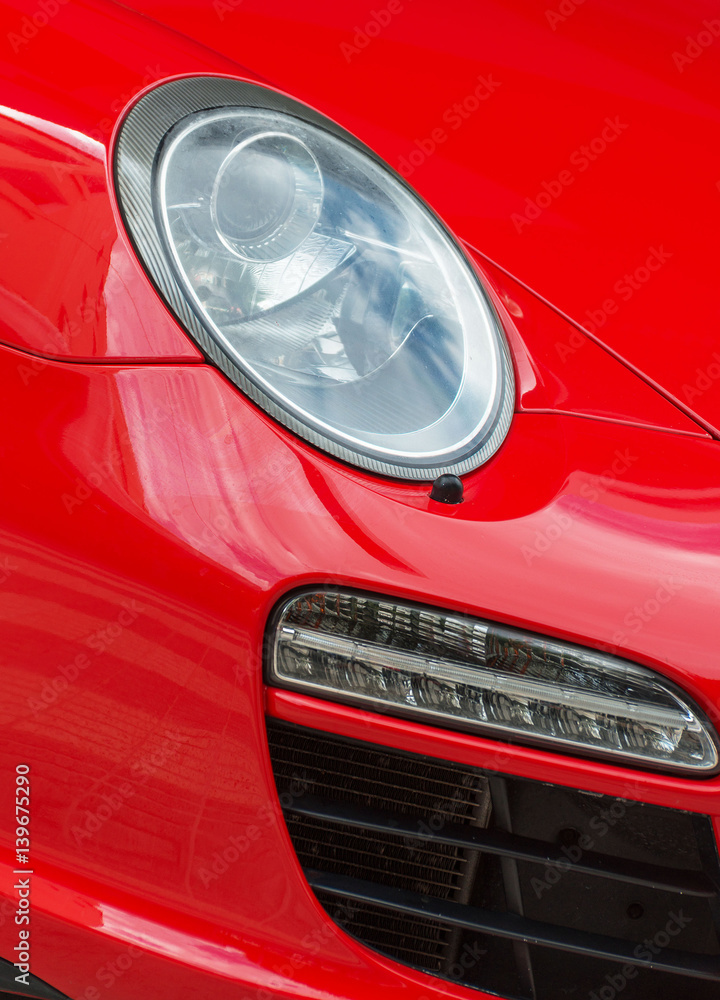 Close-up view of red sports car headlight.