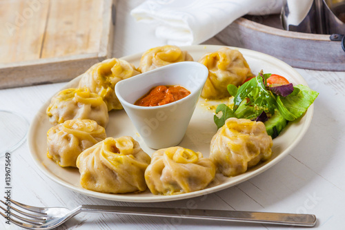 Nepalese traditional dumpling momos served with tomato chatni and fresh salad.
