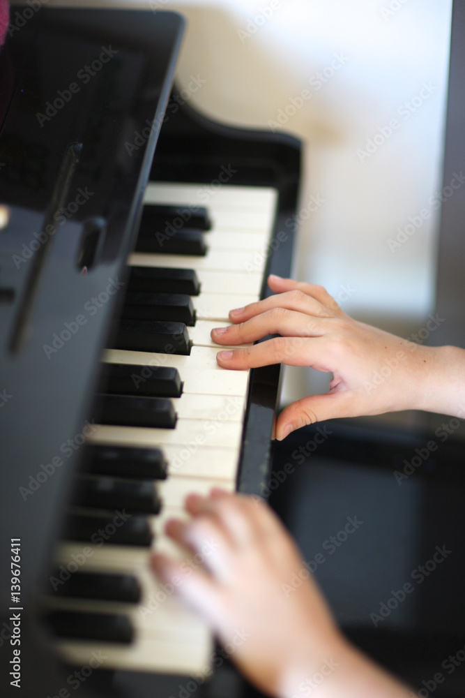 Obraz premium Hands of the child on the keys of a toy piano.