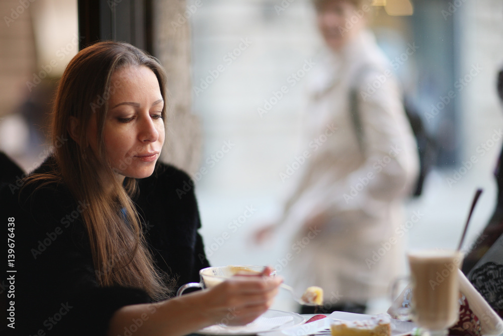 Woman in a cafe by the window for dessert. Woman in a cafe by the window for dessert.