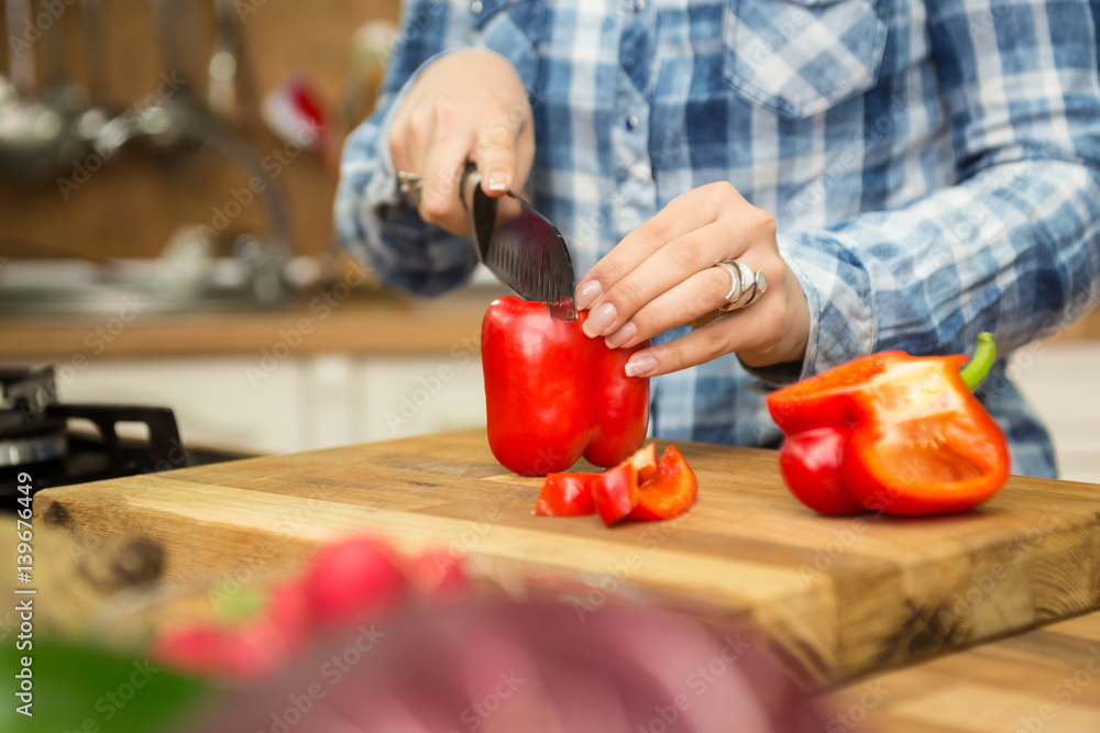 Woman chopping bell pepper and cooking in the kitchen. Woman chopping bell pepper and cooking in the kitchen.