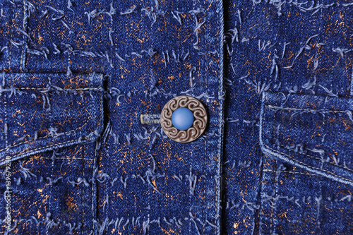 Texture of blue denim with gold threads. Beautiful blue button, pockets