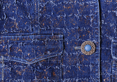 Texture of blue denim with gold threads. Jeans. Beautiful blue button, pockets