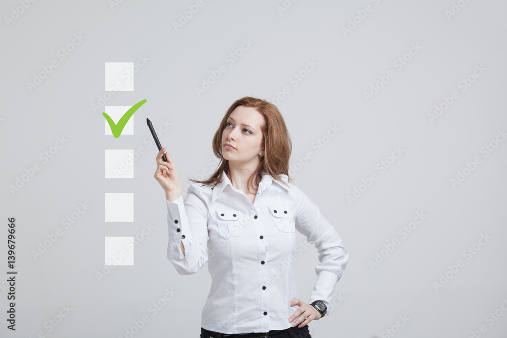 Young business woman checking on checklist box. Gray background. Young business woman checking on checklist box. Gray background.