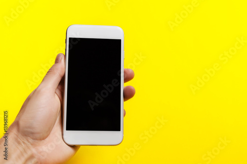 hand holding phone on on a yellow background.  clipping path inside