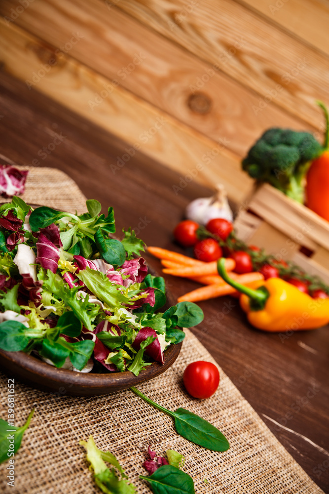 Provence salad. Leaves of endive or chicory, lamb and rose salad. Cherry tomato, pepper and carrot. Raw vegetables. On wooden table. Provence salad. Leaves of endive or chicory, lamb and rose salad. Cherry tomato, pepper and carrot. Raw vegetables. On wooden table.
