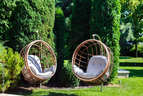 Two hanging chairs in garden on sunny summer day.