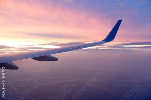 View of jet plane wing with cloud patterns