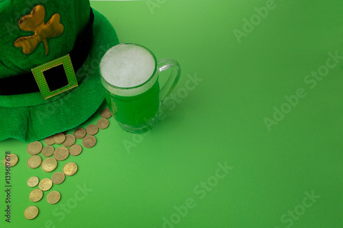 St Patrick's Day green beer with shamrock, pot with gold coins, horseshoe and Leprechaun hat against green background. photo