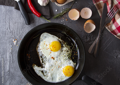fried eggs iron frying pan rosemary spice pepper
