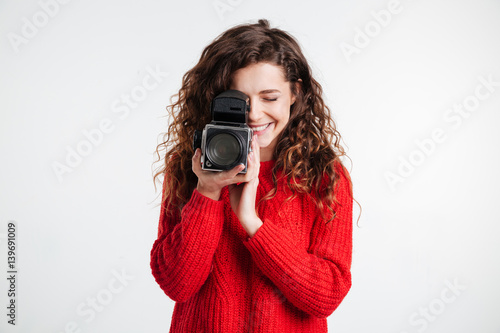 Portrait of a young smiling woman filming with retro camera