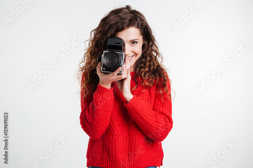 Portrait of a young smiling woman filming with retro camera
