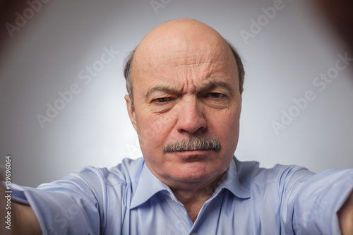 Aged man dissatisfied frowns and looks sullenly. Wrinkles on the forehead of negative events photo