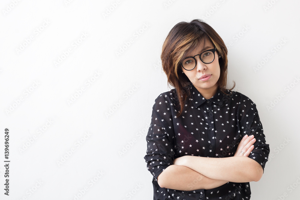 Self-confident asian woman in black shirt with stars standing the wall, arms crossed Self-confident asian woman in black shirt with stars standing the wall, arms crossed