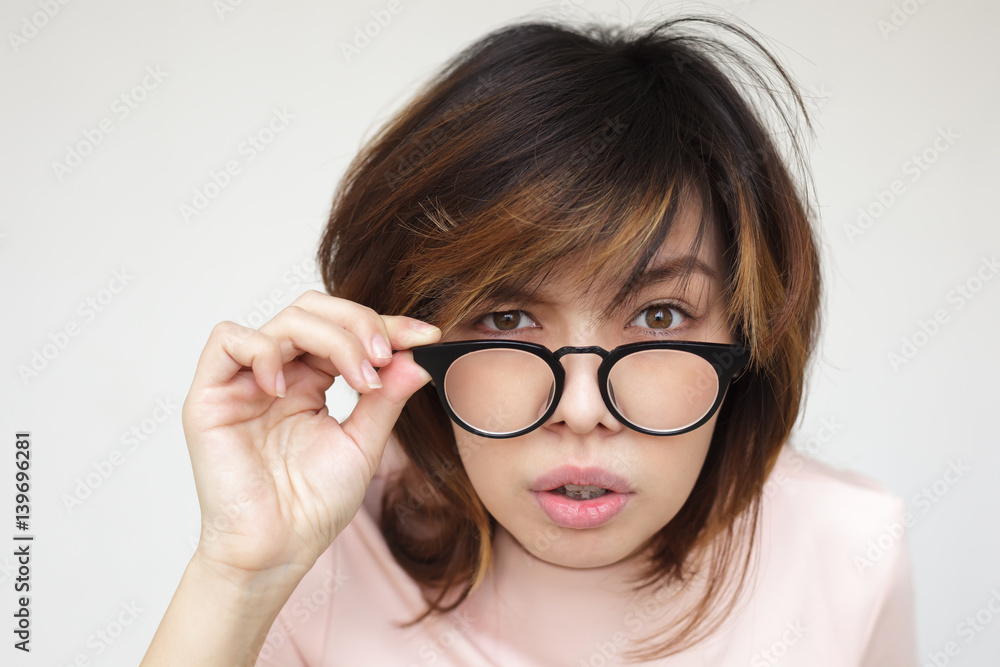 Japanese girl looks questioningly, surprised takes off her glasses