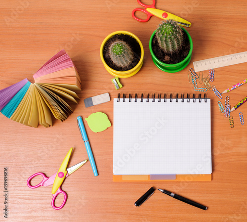Top view of office tools with blank notebook on wooden table
