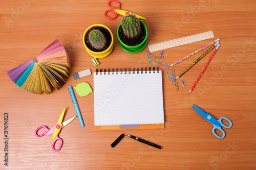 Top view of office tools with blank notebook on wooden table