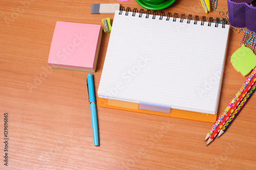 Top view of office tools with blank notebook on wooden table
